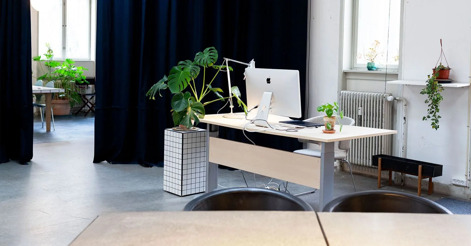 A workspace with a monitor and plants, with the curtain in the background.